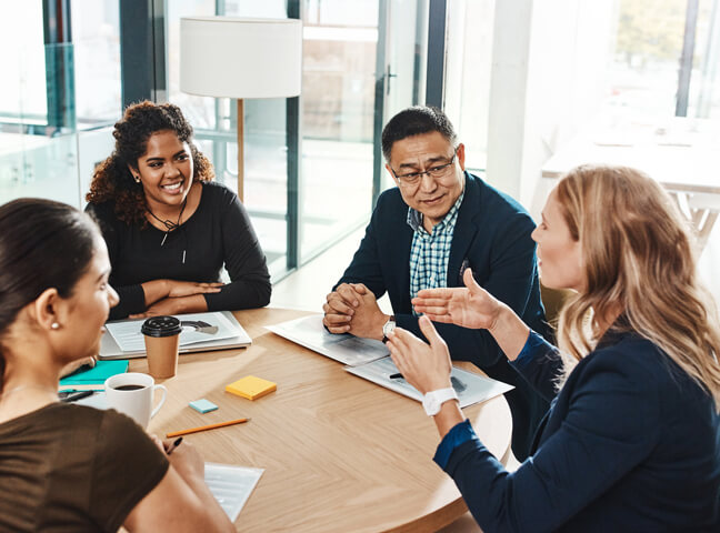 Individuals At A Desk Discussing Employer Health Insurance Options