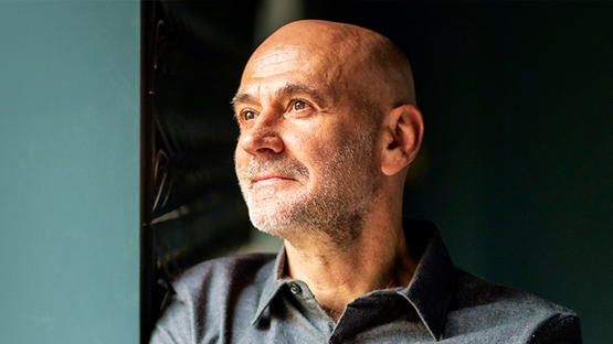 A man looks out window with sun shining on his face.